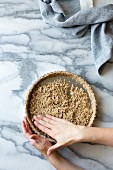 Person prepares a gluten free tart crust, made from sliced almonds, shredded coconut, salt and maple syrup
