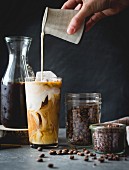 Woman pouring milk in to an iced coffee