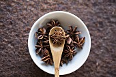 Star anise with a wooden spoon in a bowl (seen from above)