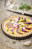 Vegan courgette tart with cashew nuts and red onions in a flan tin