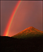 Rainbow over hills at sunset