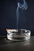 Cigarette on ash tray with smoke