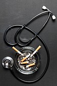 Cigarettes in ash tray with stethoscope