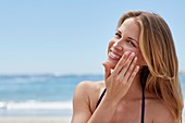 Woman applying sun cream on beach