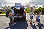 Family unpacking the car by the beach