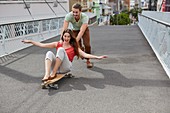 Woman on skateboard,man pushing