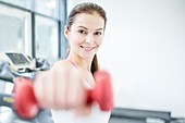 Smiling young woman holding dumbbell
