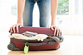 Woman pushing down on full suitcase