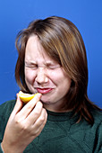 A Woman Biting Into a Lemon