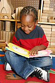Boy Reads Book in Day Care