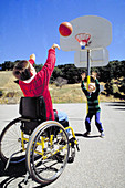 Disabled boy in wheelchair shoots hoops