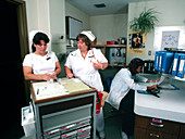 Nurses consulting over a medicine cabinet