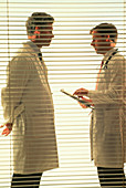 Two doctors talking behind venetian blind