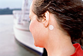 Woman at sea with anti-seasickness patch near ear