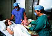 Childbirth: doctor handing newborn baby to mother