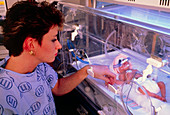 Nurse attending to premature baby in incubator