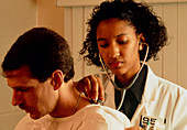 Woman GP doctor with stethoscope examines a man