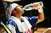 Man drinking water after a game of tennis