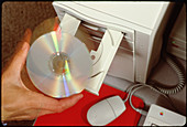 Hand inserts a CD disc into computer CD-ROM drive