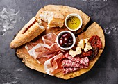 Cold meat plate with prosciutto, salami, bread and olives on wooden board