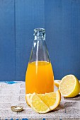 Opened glass bottle of citrus orange and lemon lemonade