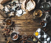 Zutaten für die Weihnachtsbäckerei: Gewürze, Mehl, Eier, Kakaopulver, Zucker, Honig und Nüsse und Ausstecher auf rustikalem Holzuntergrund