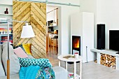 Cosy living area with fire in stove and rustic sliding door leading to kitchen