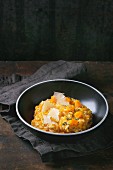 Pumpkin risotto with thyme and cheese on a dark surface