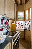 Glass-fronted wall units and porcelain sink in fitted kitchen