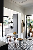 Floral-patterned floor tiles and open terrace doors in black fitted kitchen