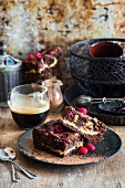 Zwei Stücke Schokoladen-Himbeer-Brownie-Käsekuchen auf schwarzem Teller