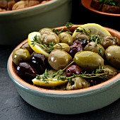 Marinated olives with thyme and lemon served as tapas in a dish