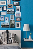 Various framed photos hung in salon style on blue bedroom wall