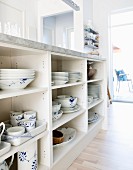 Blue and white crockery in open-fronted shelves below kitchen counter