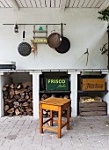 Firewood store, various wooden crates and pans hung on wall in rustic outdoor kitchen