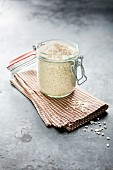 Short-grain rice for rice pudding in a preserving jar on a tea towel