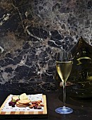 Glass of Champagne in front of spherical vase and marble wall