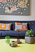 Retro cups on coffee table in front of patterned scatter cushions on sofa