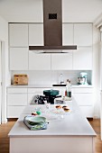 weiße Einbauküche mit Oberschränken, Dunstabzug und Kücheninsel