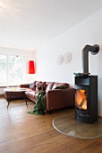 Lit fire in stove next to brown leather sofa