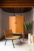 Easy chair with woven seat and wooden retro cabinet in semicircular room
