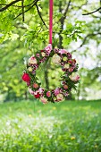 Wreath of flowers hung from branch in summer meadow