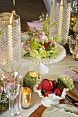 Festliche Tischdekoration mit Kerze im Glas und Blumen