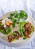 Ginger and chilli pork in lettuce cups topped with a poached egg