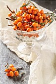 Fresh sea buckthorn berries with twigs in a glass bowl
