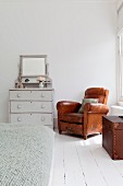 Brown leather armchair in corner of white bedroom