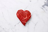 A heart-shaped cut of fresh beef on a marble surface