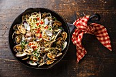 Spaghetti alle Vongole Seafood pasta with clams in cast iron frying pan on wooden background