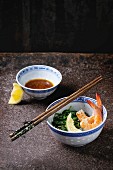 Chinese bowls with Cooked spinach and fried shrimps prawns with lemon and sesame seeds, soy sauce and chopsticks