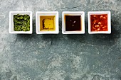 Verschiedene Saucen in Schälchen: Kärutersauce, Pfeffer-Öl-Vinaigrette, Austernsauce und Mignonette-Sauce
